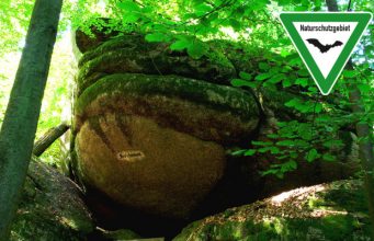 The Froschmaul rock formation in Falkenstein Schlosspark, Germany, with nature reserve sign