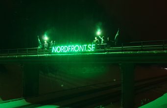 Nordic Resistance Movement members hold a glowing banner atop a bridge in Ludvika, Sweden