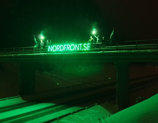 Nordic Resistance Movement members hold a glowing banner atop a bridge in Ludvika, Sweden