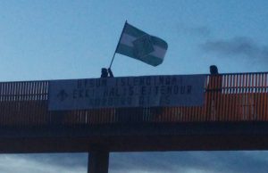 Nordic Resistance Movement members in Iceland hold a banner and flag on a bridge