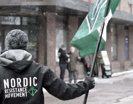 A Nordic Resistance Movement member holds a Tyr Rune flag in Horten, Norway