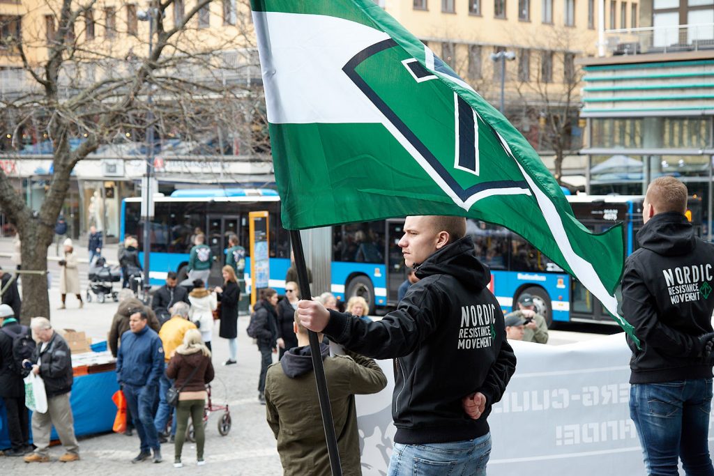 A Nordic Resistance Movement activist holds a flag in Stockholm