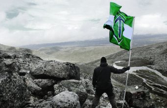 Man holds a Nordic Resistance Movement flag in the mountains