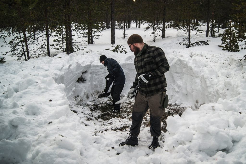 Digging a space for a tent in the snow in a Swedish forest