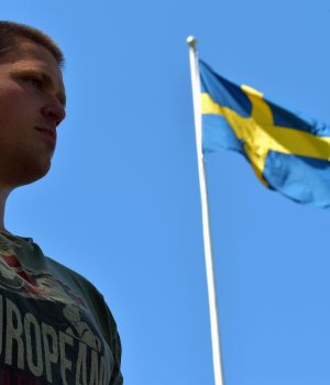 Nordic Resistance Movement activist in front of Swedish flag