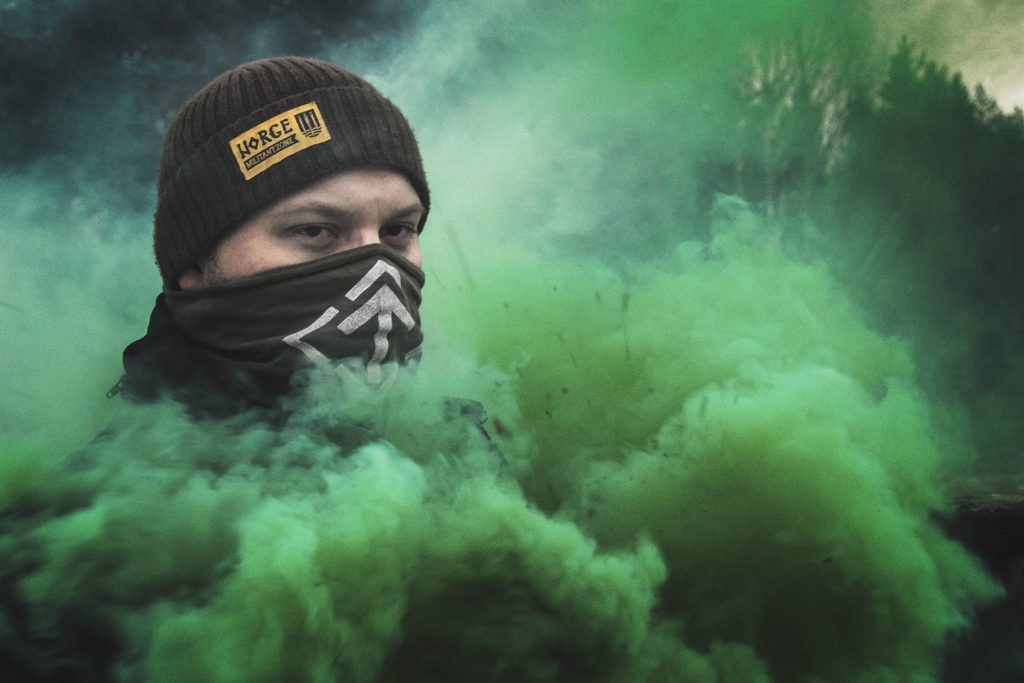 Nordic Resistance Movement activist surrounded by green smoke during activism