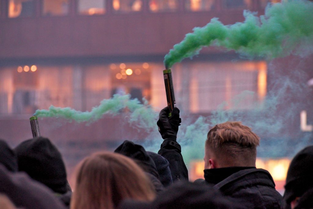 Nordic Resistance Movement activists at vaccine passport demonstration, Stockholm. Green flare.