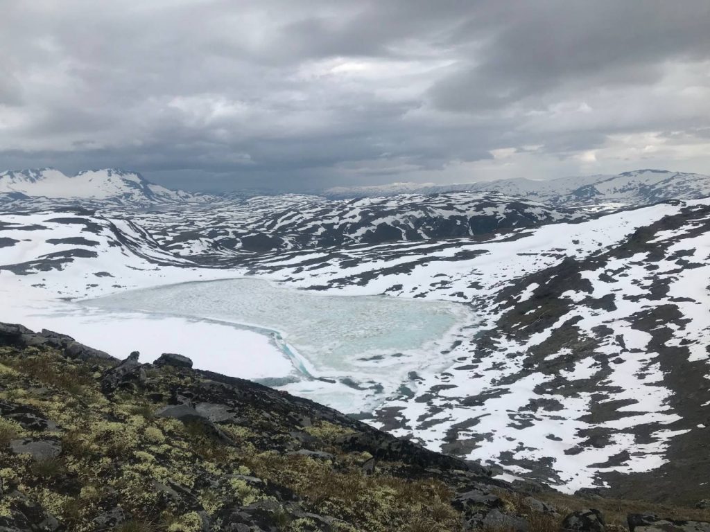 A frozen lake surrounded by mountains in Jotunheimen, Norway